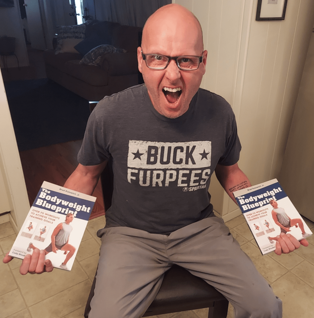 Personal trainer Shane McLean holding two copies of a book he wrote.